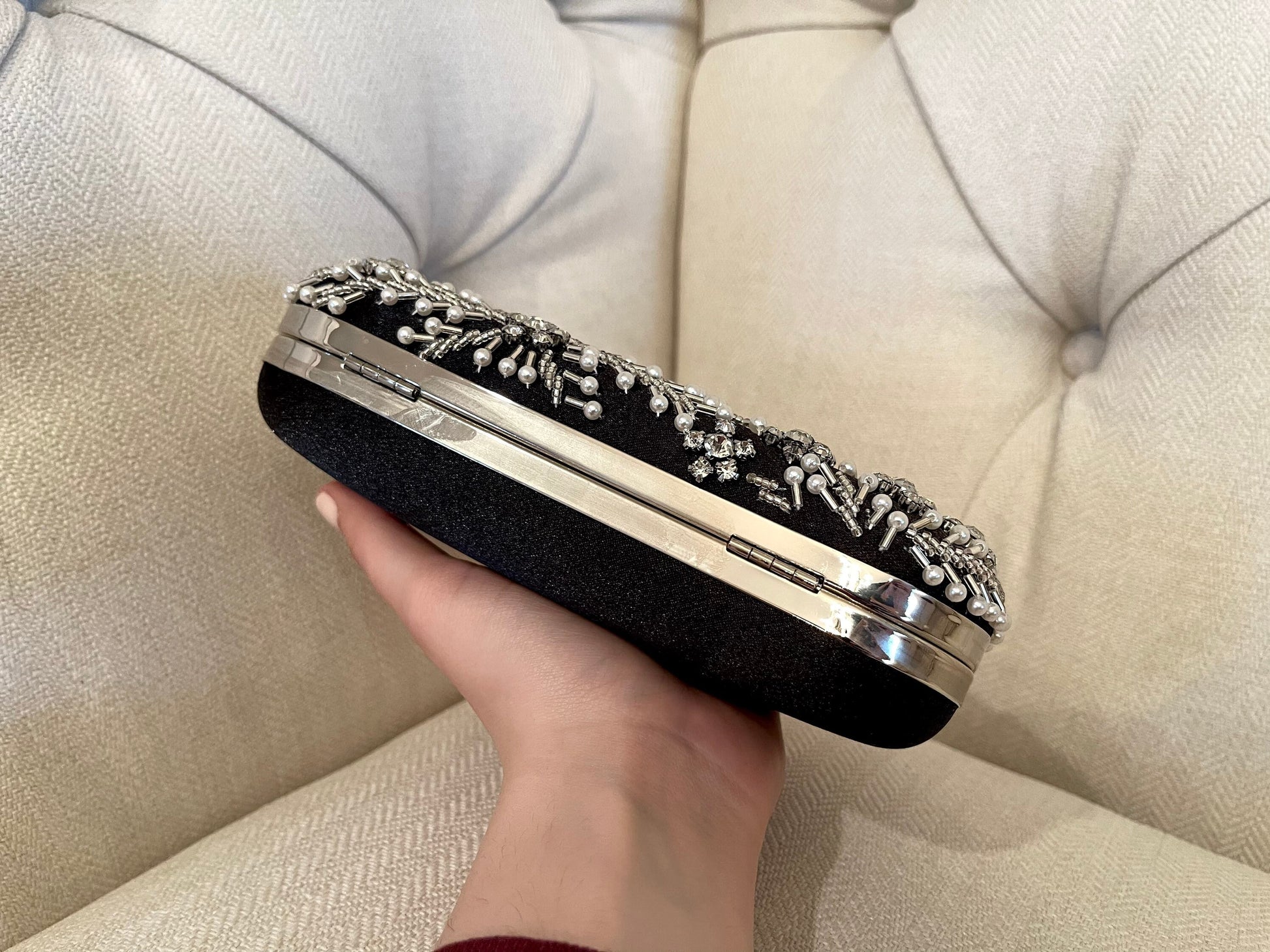 Black clutch bag displayed upside down to showcase the underside design and texture against a neutral background.