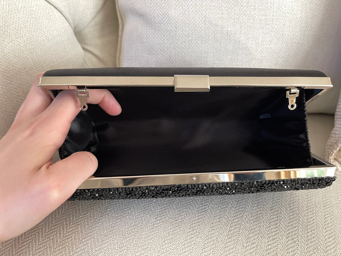 Interior view of black shimmer clutch bag with chain, showcasing the spacious compartment and sleek design against a white background