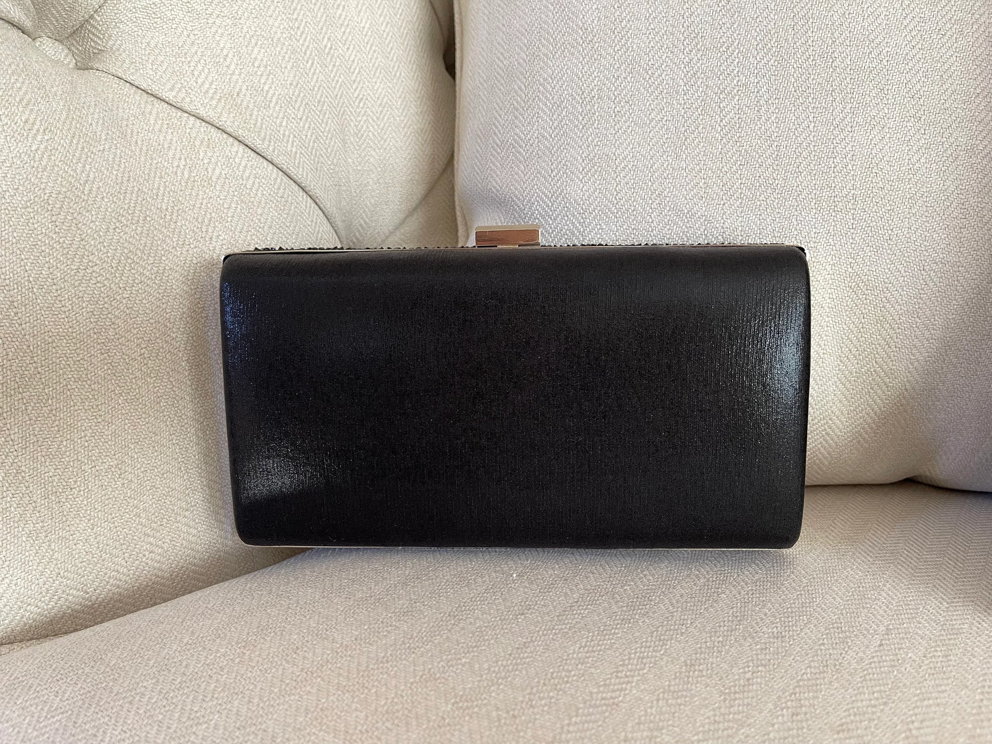 Black shimmer clutch purse showing the plain back against a white background