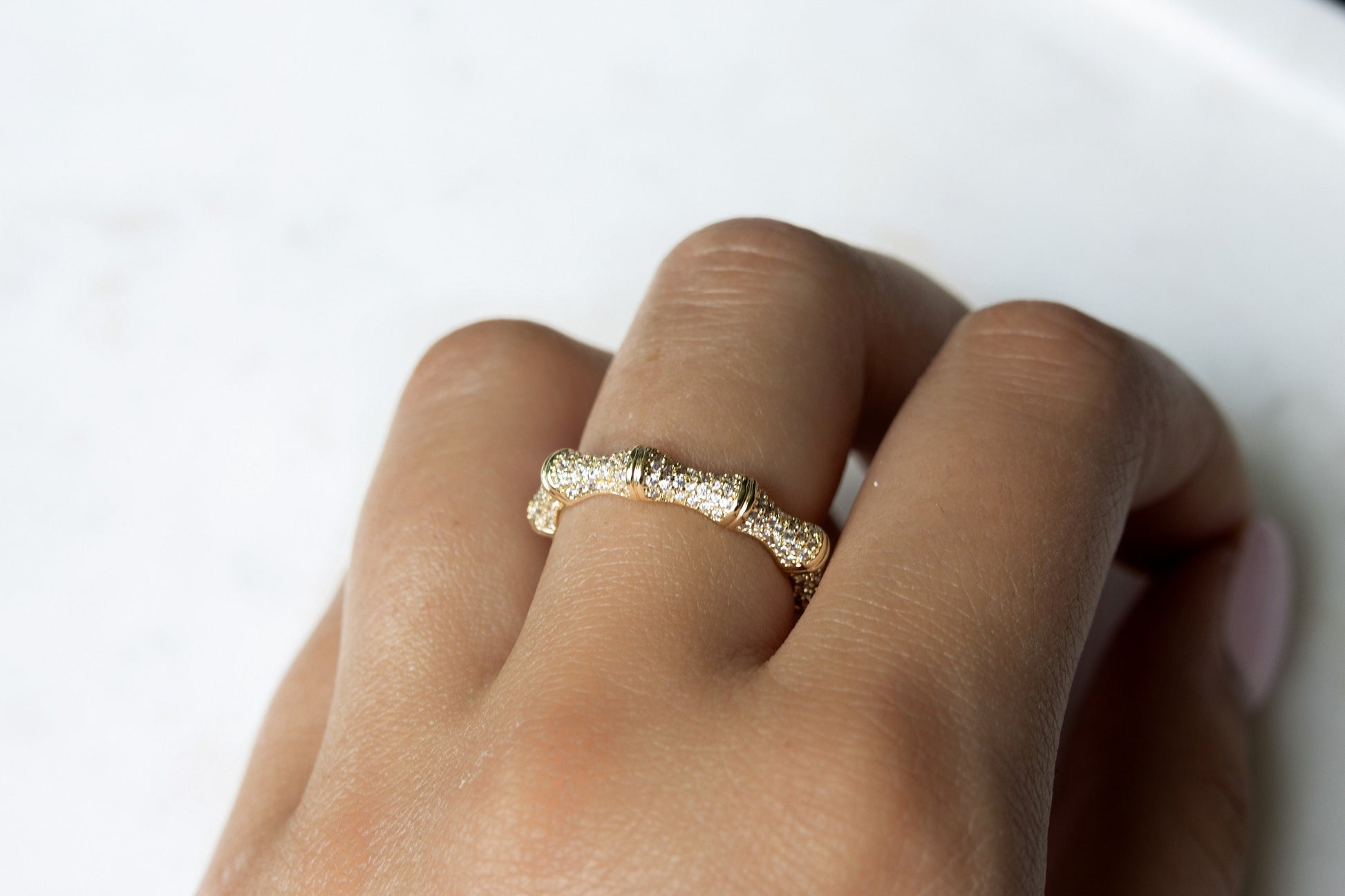 Thin pave ring modeled on a hand, showcasing its elegant design against a white background.