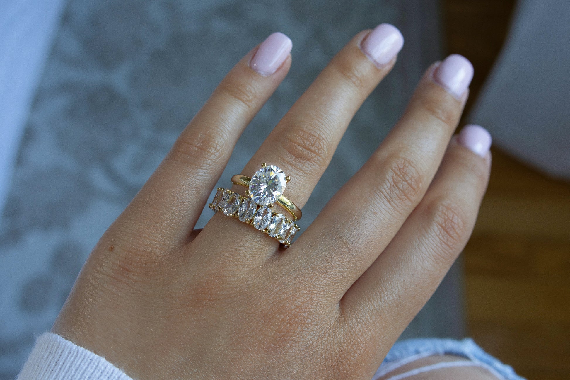 Model showcasing 3CT Oval Moissanite Engagement Ring in Yellow Gold stacked with another ring