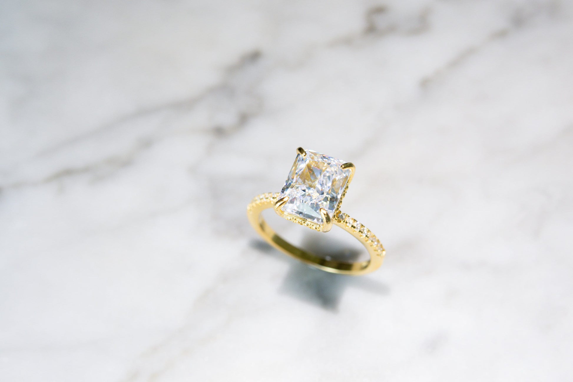 Top-down view of the gold Radiant Cut Engagement Ring on a marble background, highlighting its luxurious design and quality.