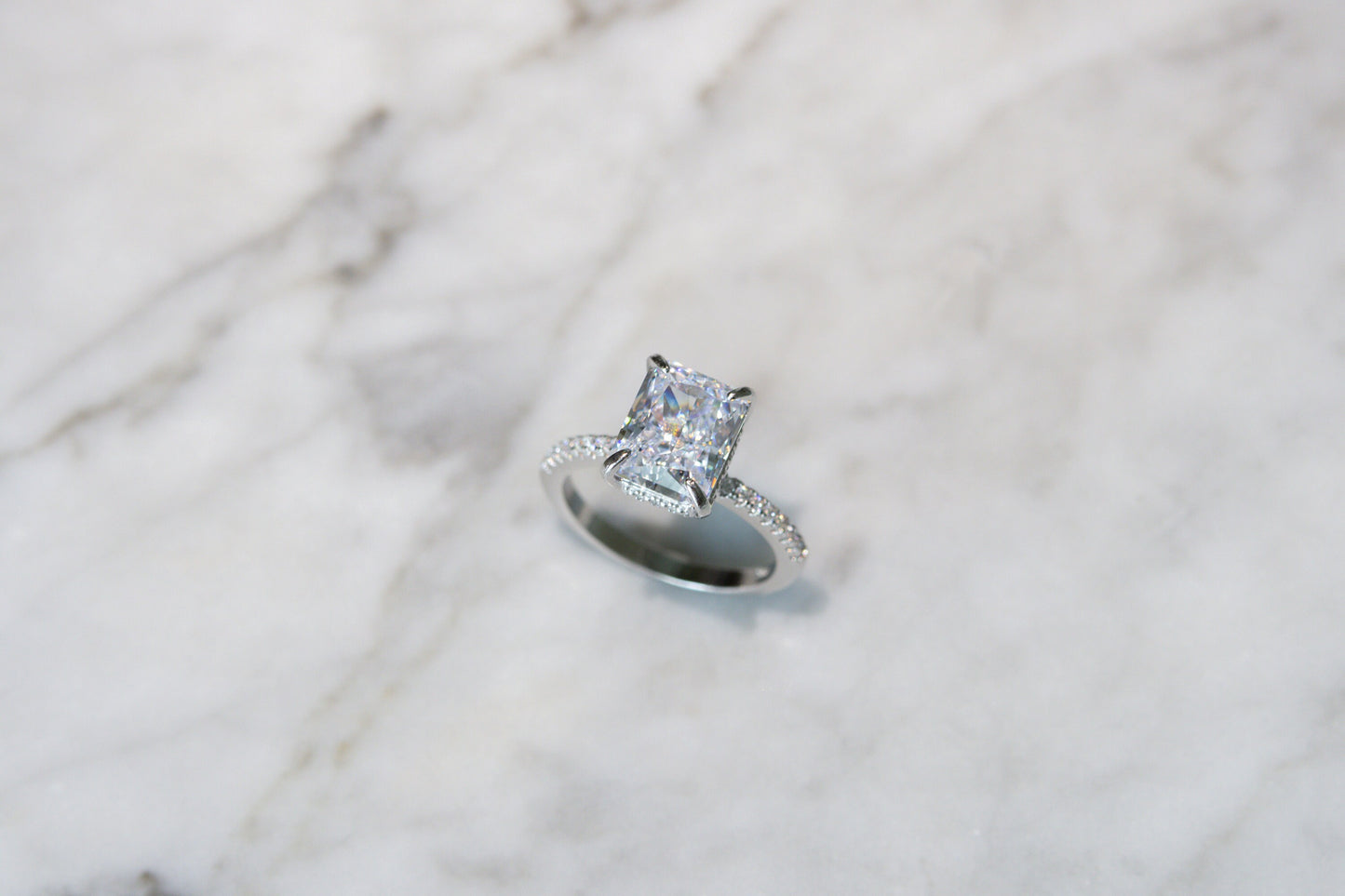 Top-down view of the silver Radiant Cut Engagement Ring on a marble background, highlighting its luxurious design and quality.