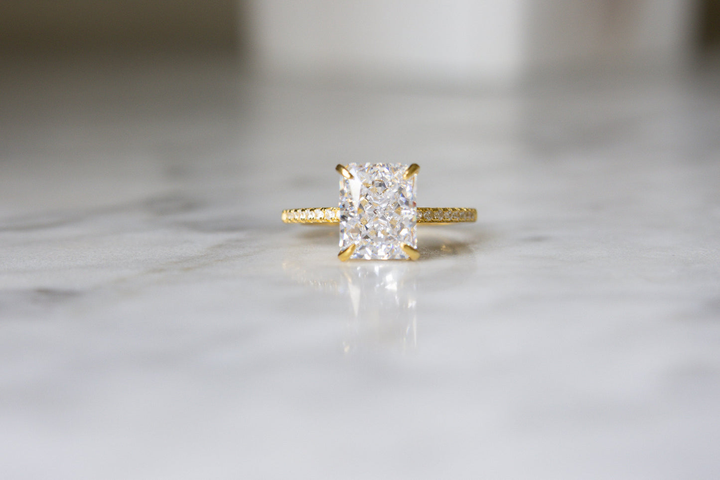 Head-on view of the gold Radiant Cut Engagement Ring on a marble background, showcasing its stunning brilliance and intricate design.