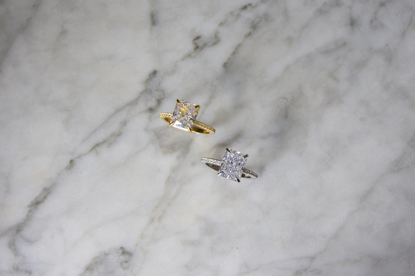 Top-down view of silver and gold Radiant Cut Engagement Ring on a marble background, showcasing its elegance and sparkle.