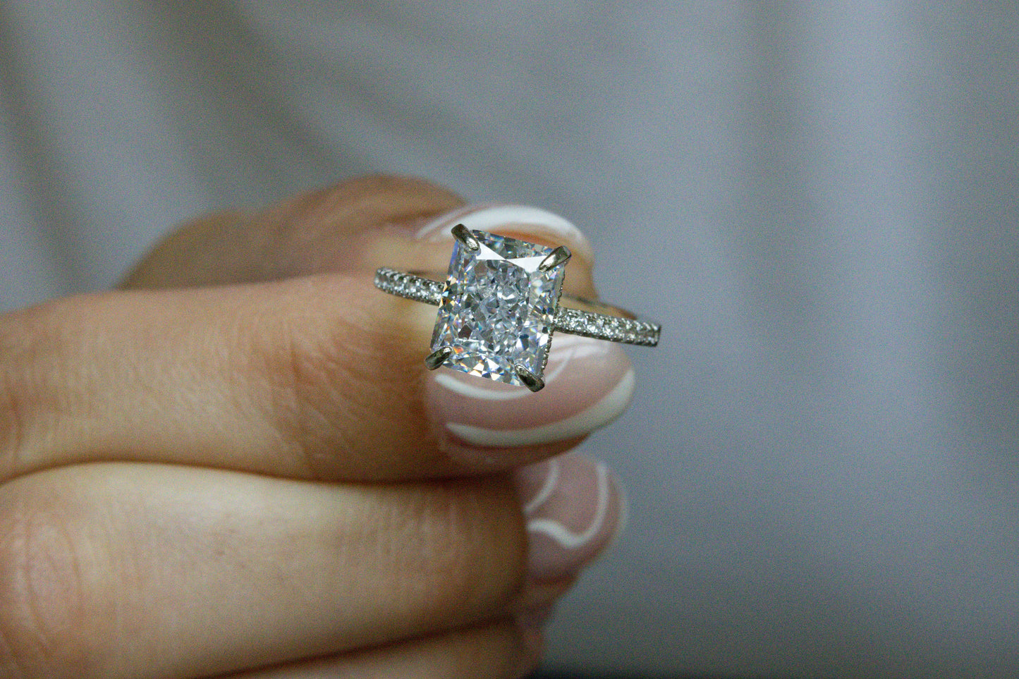 Model holding the silver Radiant Cut Engagement Ring against a white background, highlighting its elegant design and sparkle