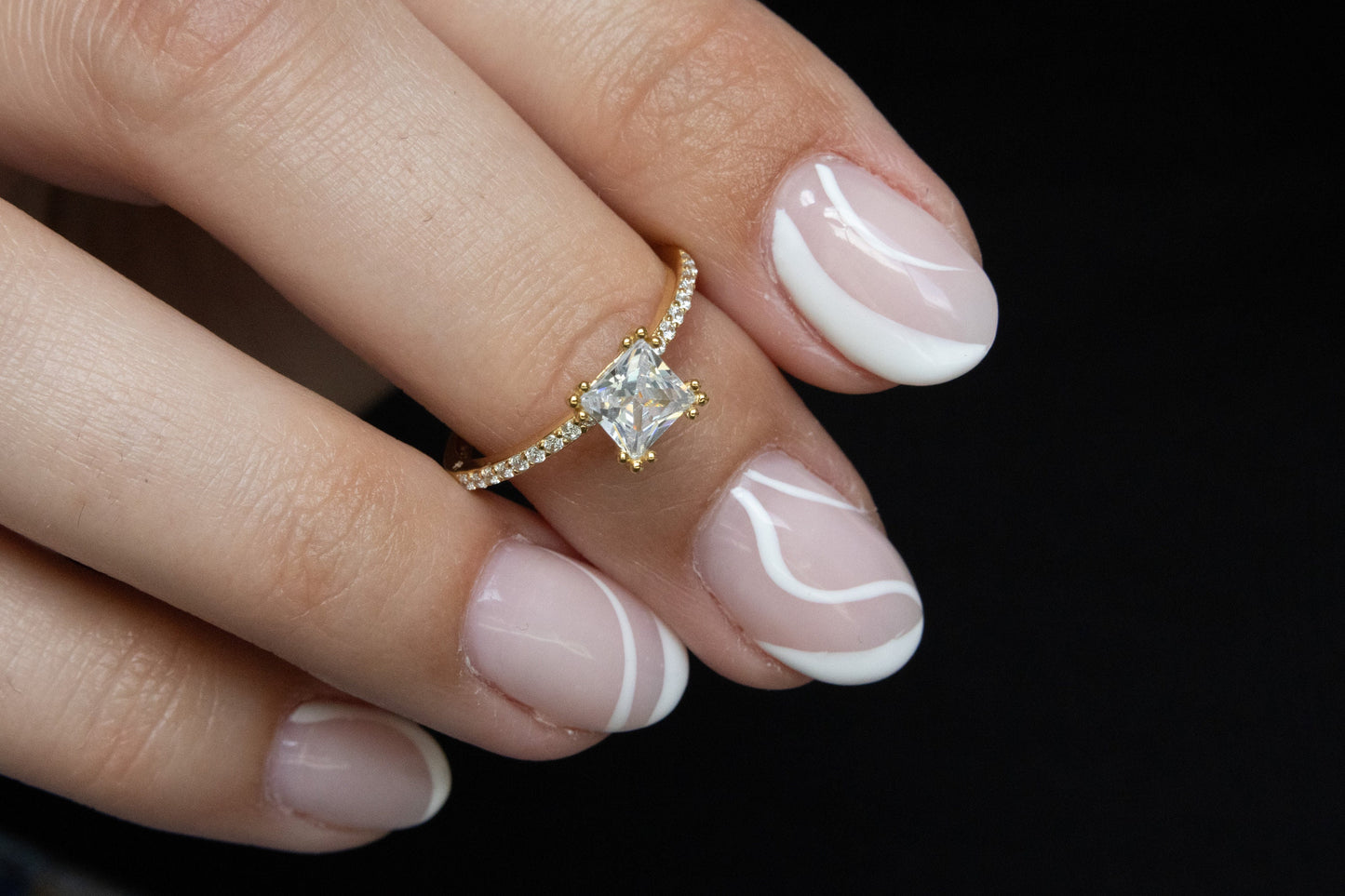 Princess Cut Ring with cubic zirconia stones on a hand, photographed against a dark background for a dramatic, elegant look.