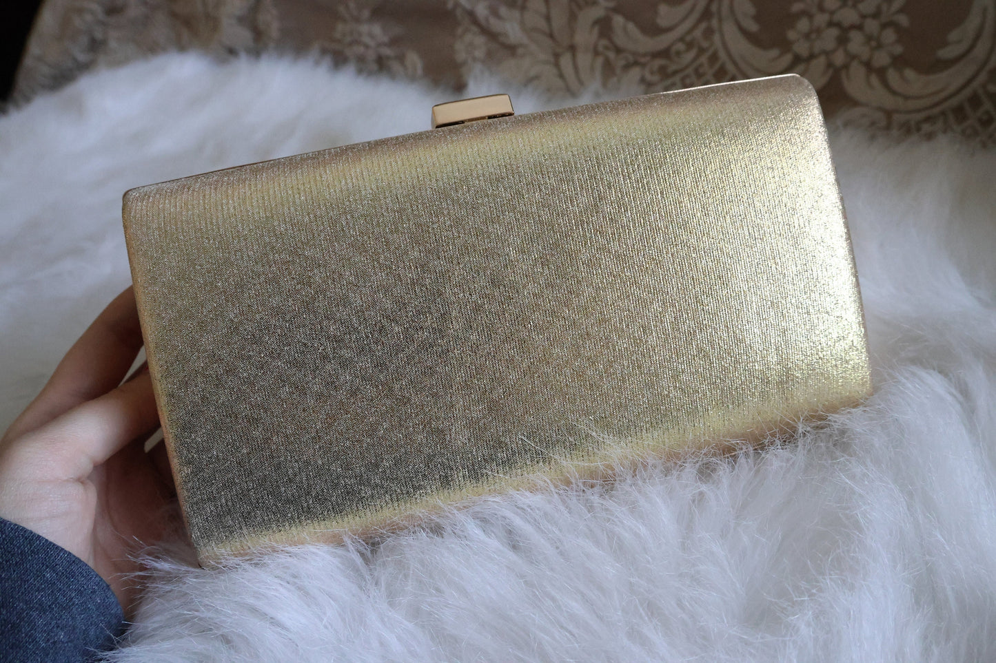 Gold shimmer clutch purse showing the plain back against a white background