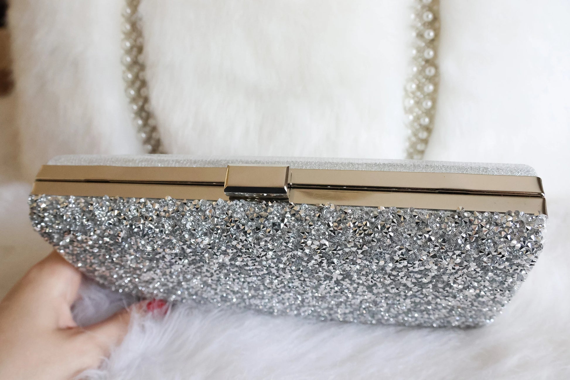 Top clasp of the silver shimmer clutch purse showcasing elegant design details against a white background.