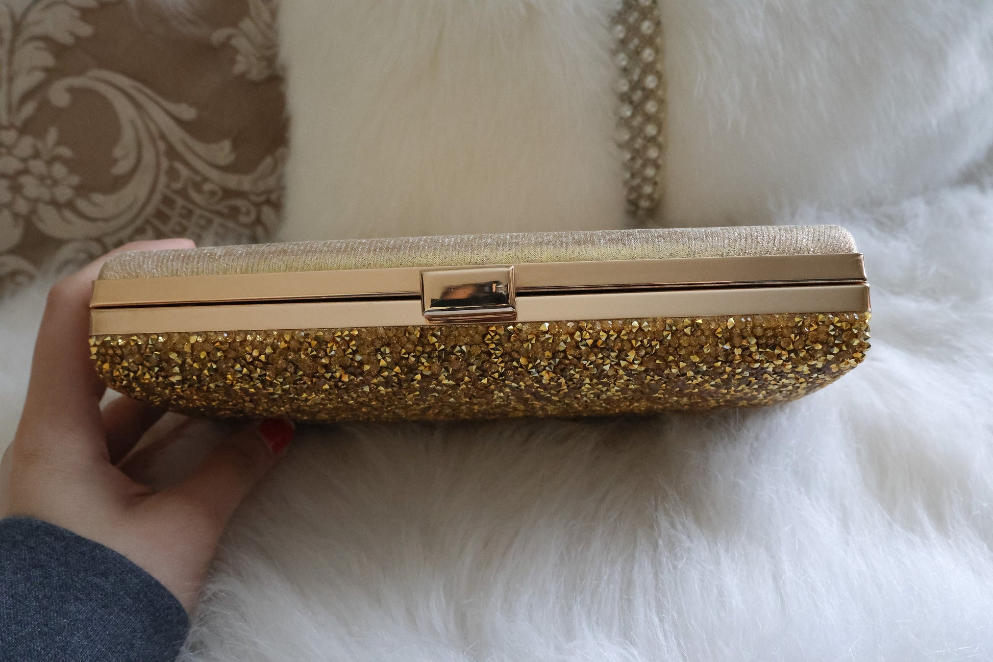 Top clasp of the gold shimmer clutch purse showcasing elegant design details against a white background.