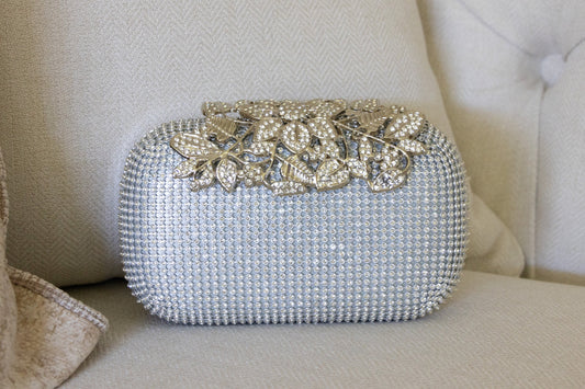 Front view of a silver crystal purse against a neutral background, showcasing the elegant design and removable chain.