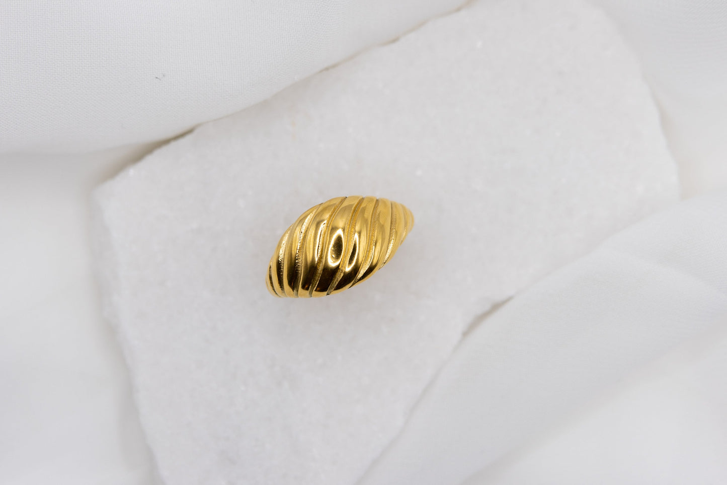 Close up of the top of the gold twisted croissant ring against a white background