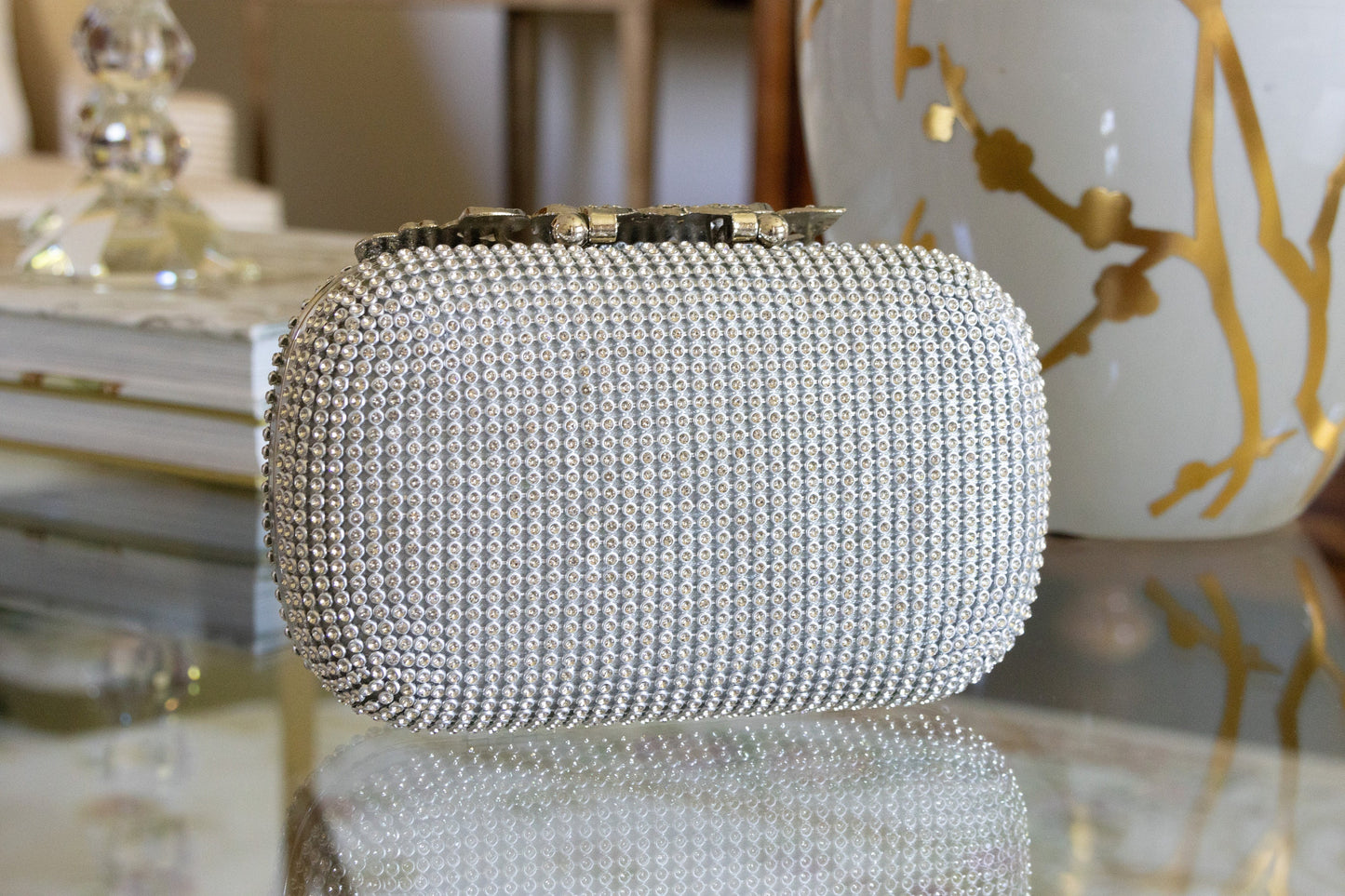 Back view of a silver crystal purse against a white and gold background, highlighting the bedazzled design and elegant finish.