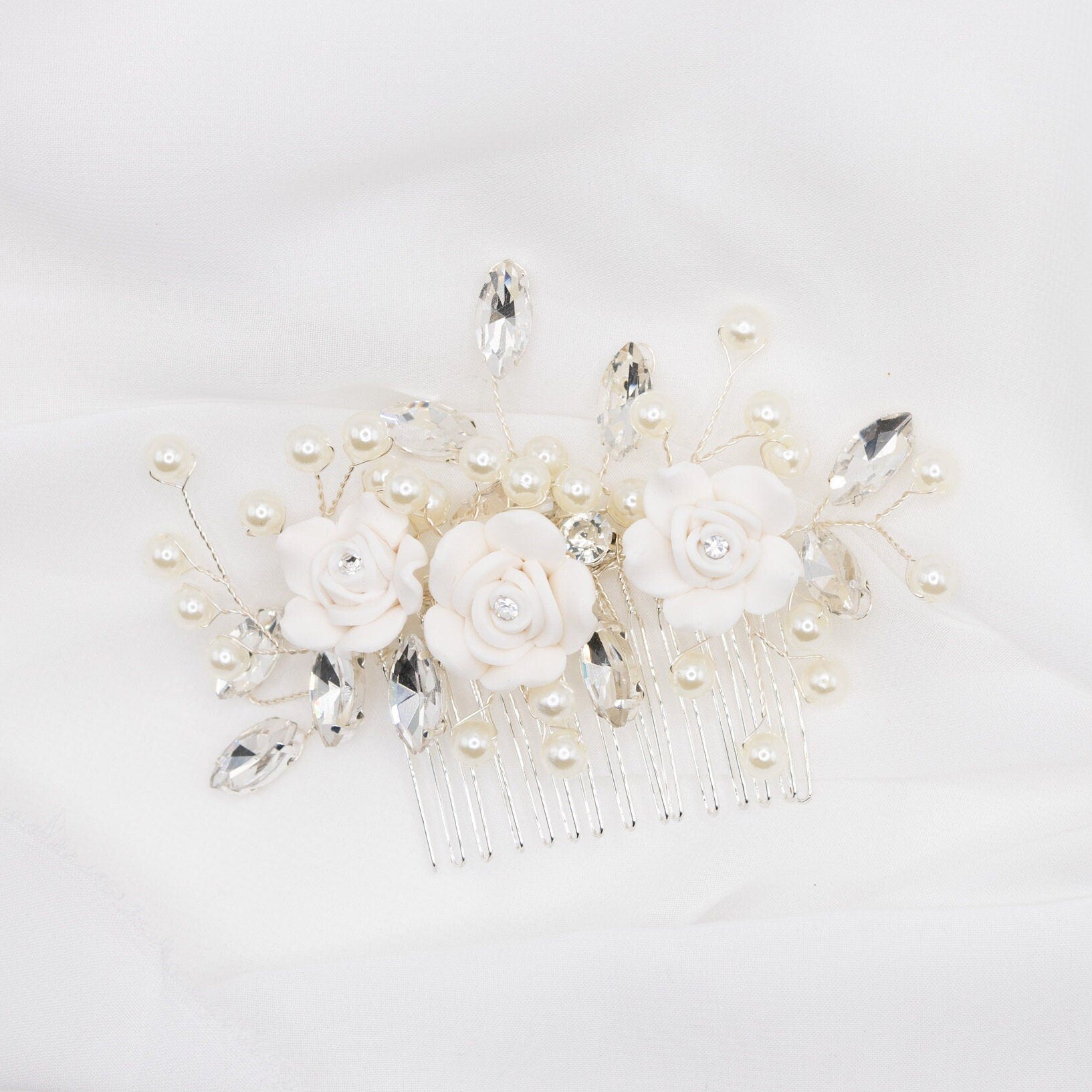 Silver floral wedding hair pin with rhinestones and faux pearls against a plain white background